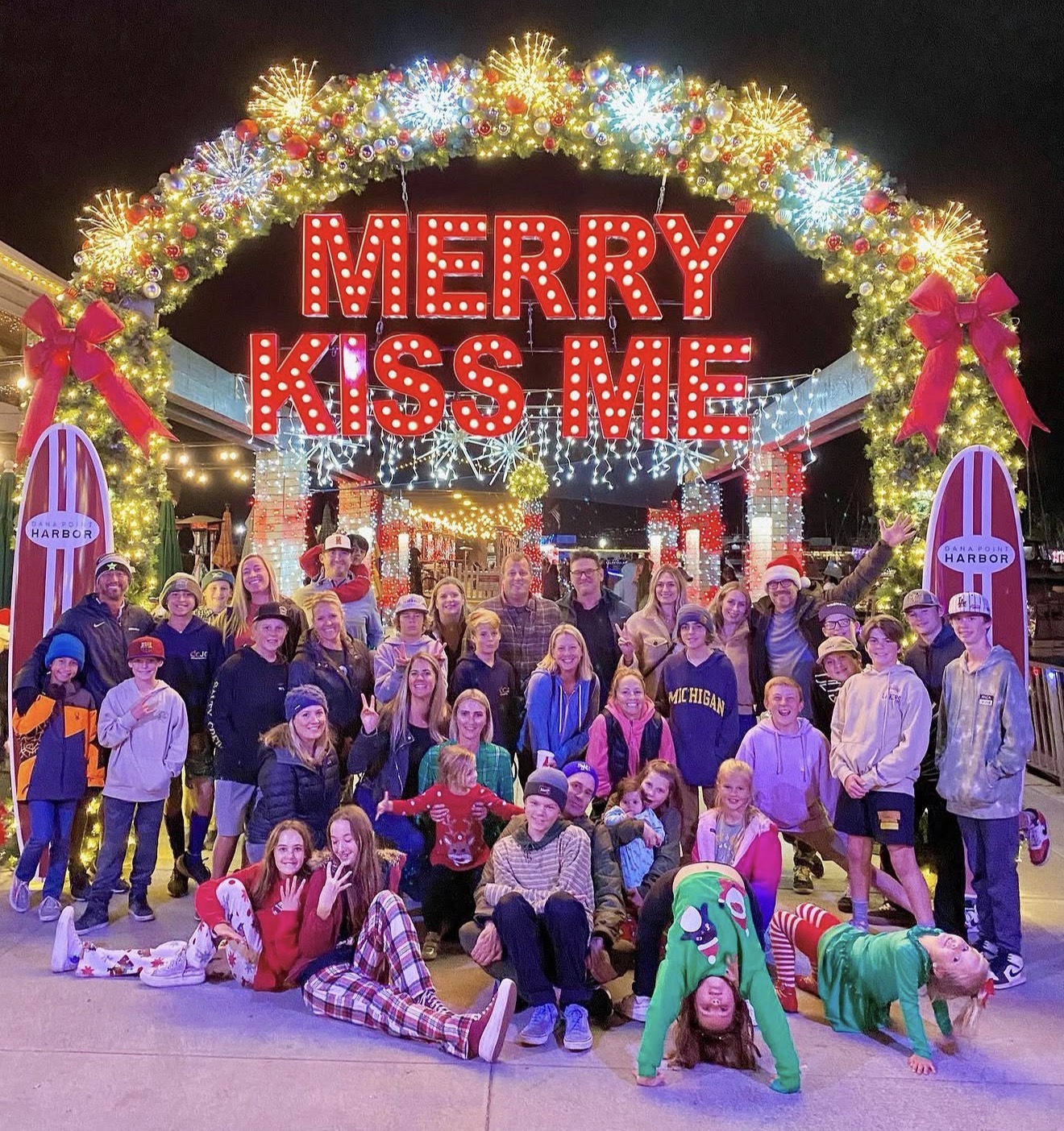 Families and friends gathered under the Merry Kiss Me display